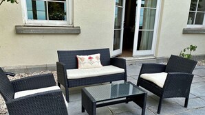 Ein Sitzbereich im Freien mit Korbmöbeln und einem Tisch mit Glasplatte.
