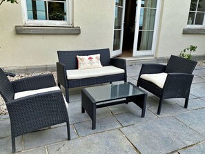 Ein Sitzbereich im Freien mit Korbmöbeln und einem Tisch mit Glasplatte.