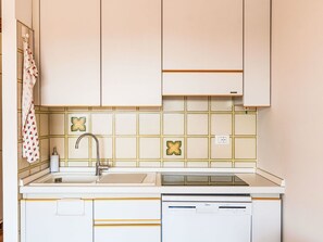 Eine kleine Küche mit weißen Schränken, einer Spüle und einem Geschirrspüler.