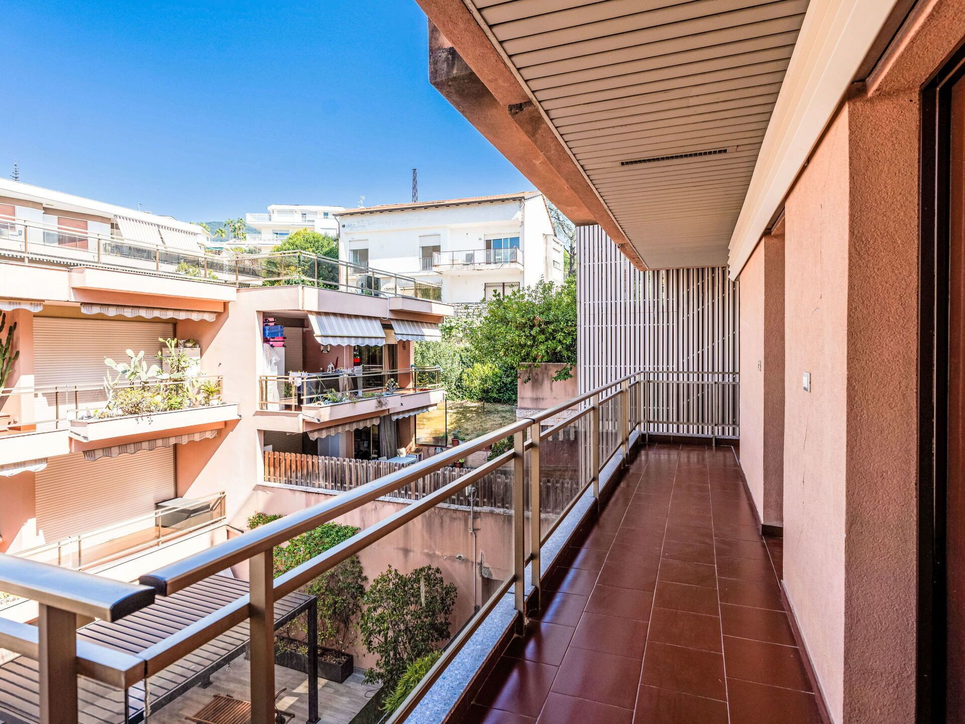 A balcony with a metal railing, a tiled floor, and a view of neighboring buildings.