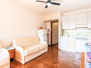Ein kompakter Wohnraum mit einer Couch, einer Küchenzeile und einem Deckenventilator.