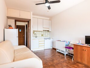 Ein gemütlicher Wohnbereich mit Küchenzeile, einer Couch, einem Esstisch und einem Deckenventilator.