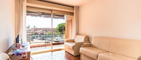 A modern living room with a sofa, a table with papers, and a view of the outside.