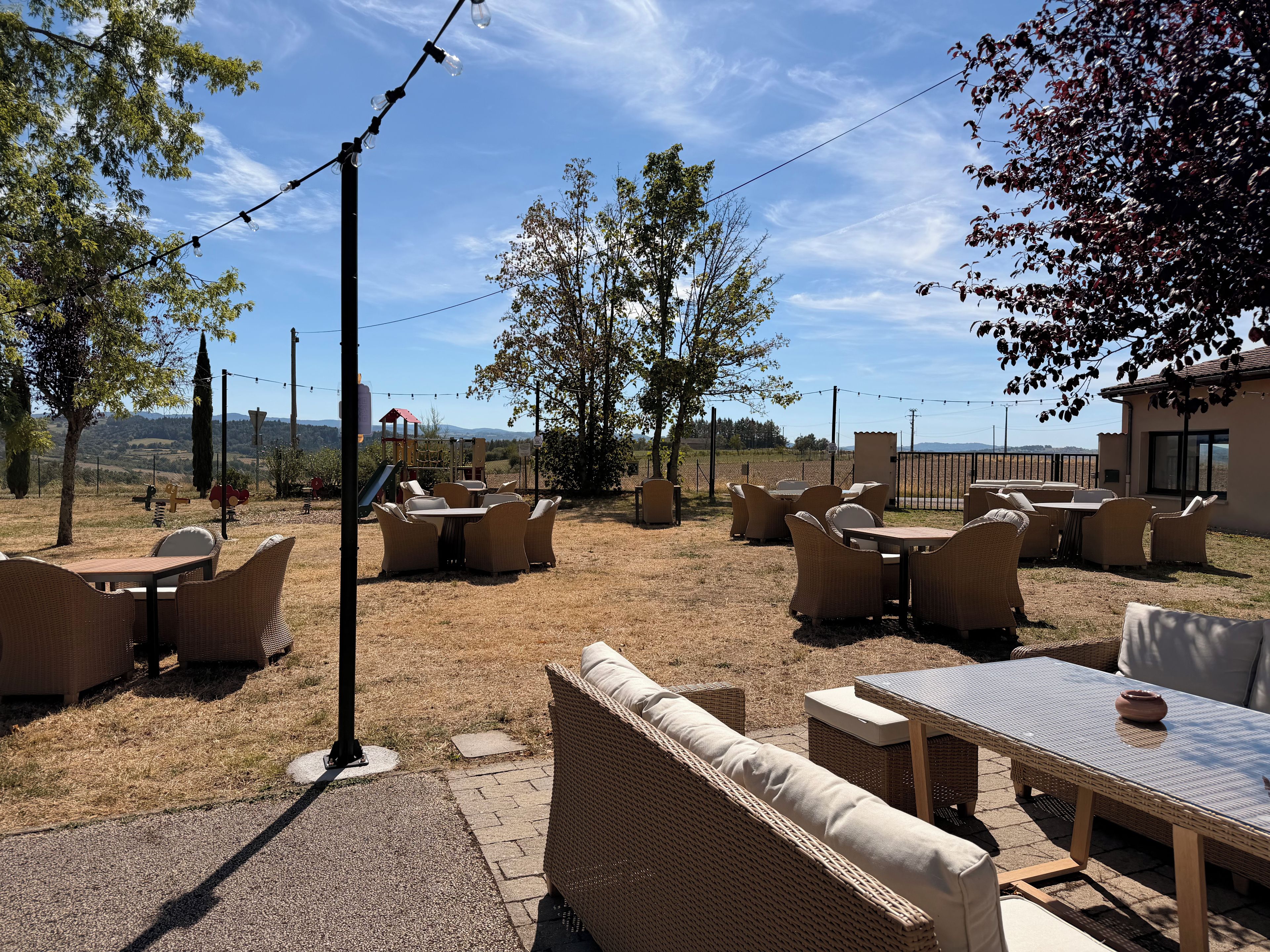 An outdoor seating area with wicker furniture and a view of the countryside.