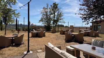An outdoor seating area with wicker furniture and a view of the countryside.