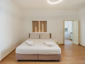 Een slaapkamer met een bed, twee kussens en twee opgerolde handdoeken.