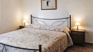 Ein Einzelbett mit blumigem Überwurf, zwei Nachttische mit Lampen und ein gerahmtes Bild an der Wand.