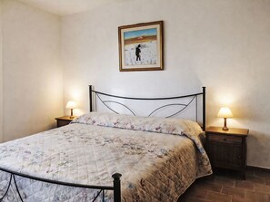A single bed with a floral quilt, two bedside lamps, and a framed picture on the wall. - Beautiful apartment for 4 guests with TV, patio and panoramic view (Collazzone)