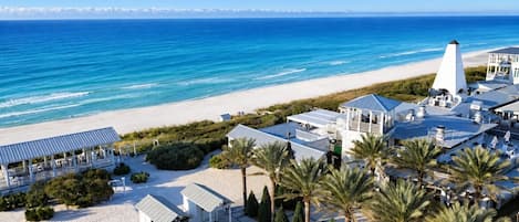 A coastal hotel with a beach view, multiple guest rooms, and a prominent lighthouse structure.