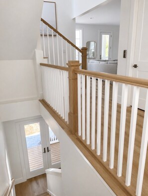 A multi-level interior with a wooden staircase and white railings. - Escape to Paradise along the Emerald Coast (Rosemary Beach)
