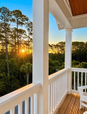 A wooden deck with a white railing overlooking a forested area during sunset. - Escape to Paradise along the Emerald Coast (Rosemary Beach)