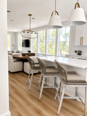 A modern kitchen with a central island, bar stools, and pendant lighting. - Escape to Paradise along the Emerald Coast (Rosemary Beach)