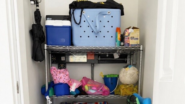 A storage unit with shelves holding various items including a blue cooler, a polka-dotted bag, and several colorful umbrellas. - Escape to Paradise along the Emerald Coast (Rosemary Beach)