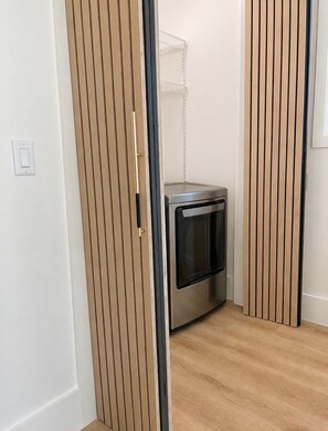 Ein kleines Zimmer mit eingebautem Backofen, Holzwandverkleidungen und einer weißen Wand.