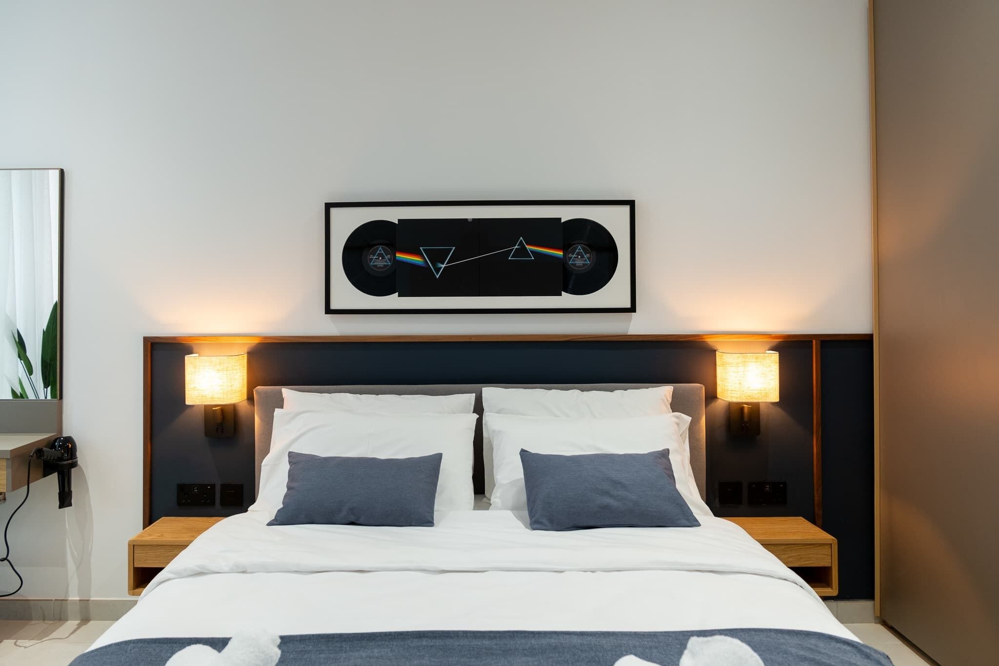 Ein modernes Schlafzimmer mit einem Bett, zwei Nachttischen und einem gerahmten Bild über dem Bett.