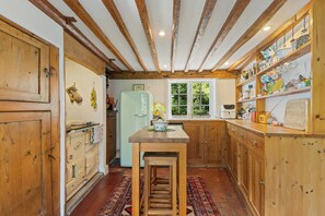 Eine Küche mit Holzausstattung, einer Mittelinsel und einem Kühlgerät im Vintage-Stil.