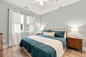 Ein Schlafzimmer mit Bett, Nachttischen, einer Lampe und einem Deckenventilator.