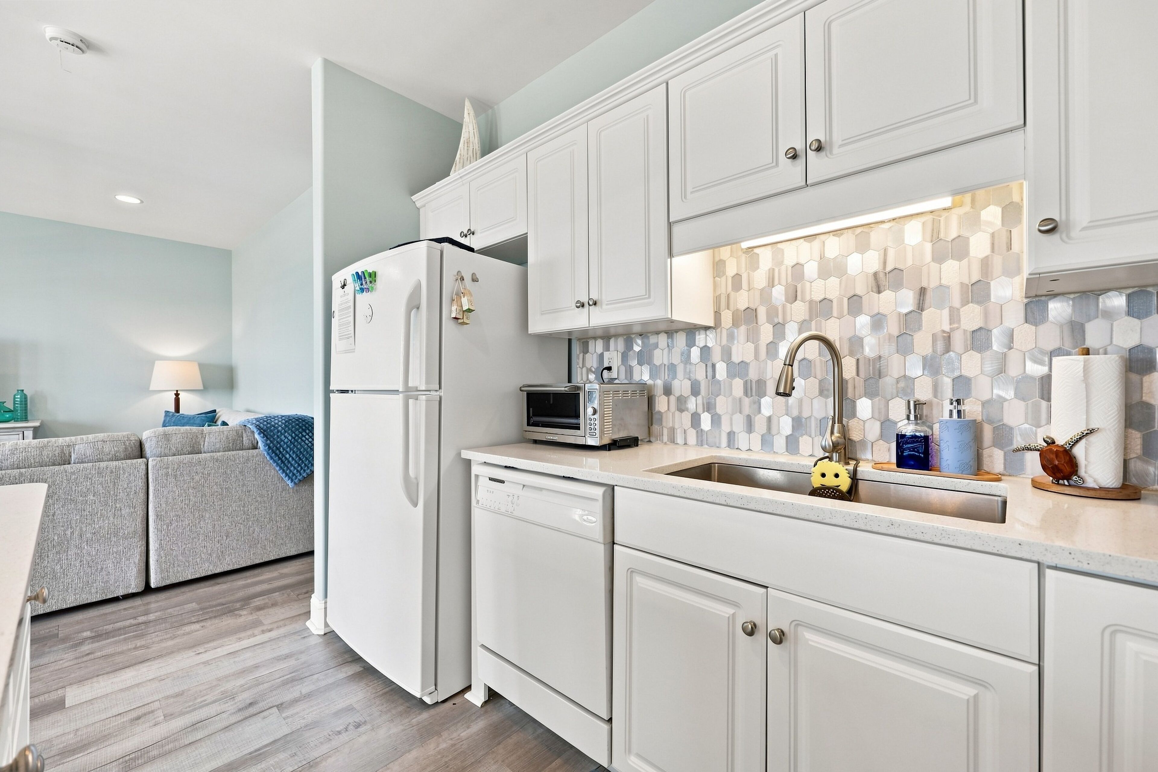 A modern kitchen with white cabinetry, a microwave, a toaster, and a sink.