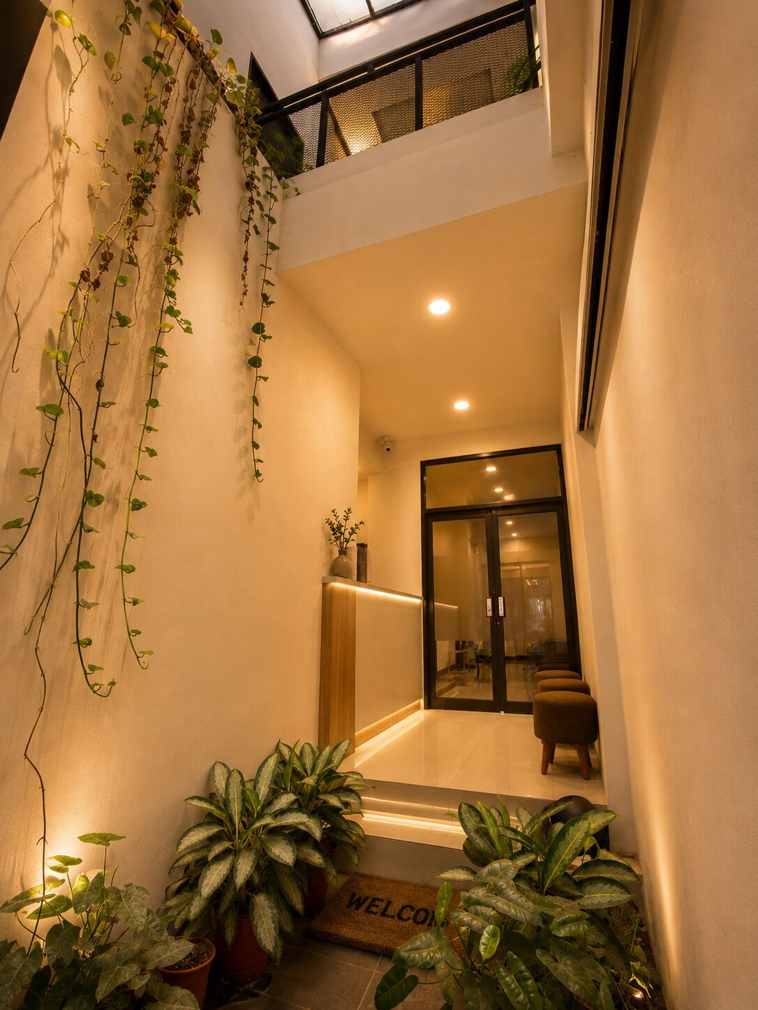 Un interior moderno con puerta de vidrio, plantas en macetas y felpudo de bienvenida.