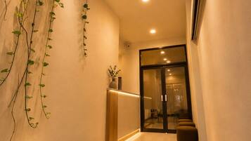 Un interior moderno con puerta de vidrio, plantas en macetas y felpudo de bienvenida.