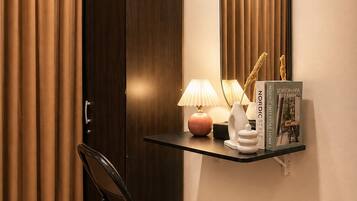 Une pièce avec une armoire en bois sombre, une chaise noire, un bureau avec une lampe et un miroir.