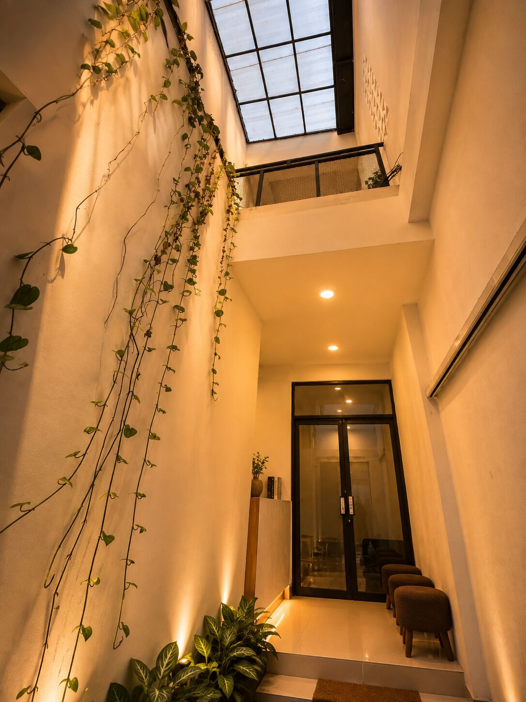 Un interno moderno con ingresso tramite porta in vetro, una scala e un lucernario.