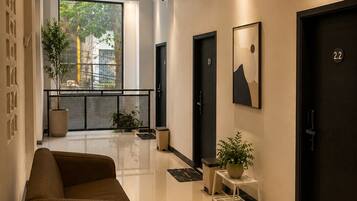 Un vestíbulo de hotel moderno con un sofá, una lámpara y una planta en maceta.