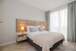 A modern bedroom with a large bed, a nightstand, and a headboard. - Holzera 6 Apartament (Warszawa)