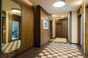 A hallway with wooden panel walls, a checkered floor, and a framed picture on the wall. - Holzera 6 Apartament (Warszawa)