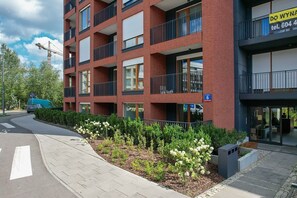 Ein mehrstöckiges Gebäude mit roter Ziegel Fassade, Balkonen und einem Schild, das auf ein Geschäft im Erdgeschoss hinweist.