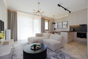 Ein modernes Wohnzimmer mit einem Ecksofa, einem runden Couchtisch und einem Essbereich mit Tisch und Stühlen.