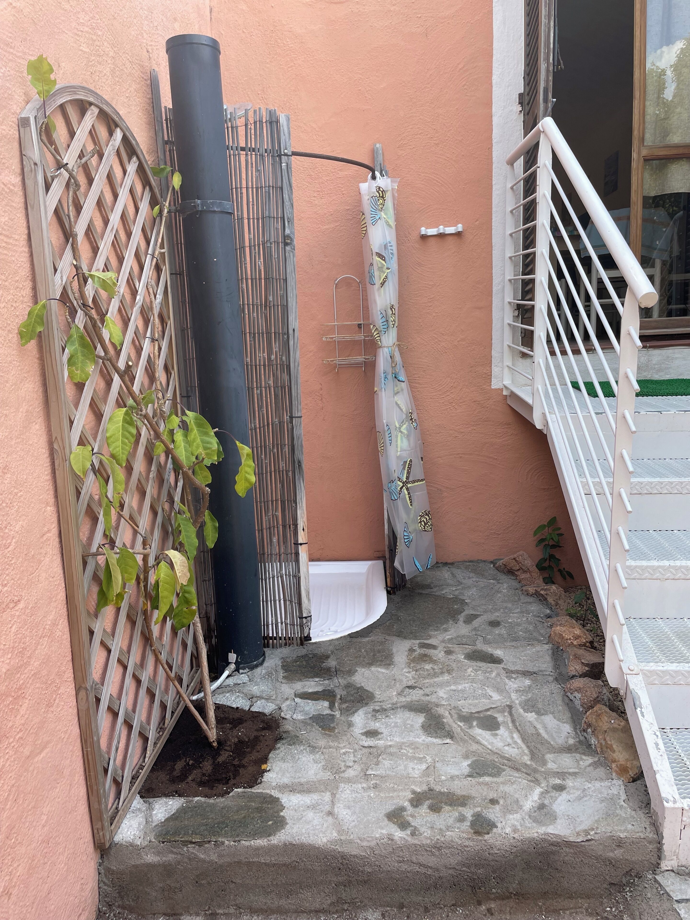 Una escala de pedra que porta a un balcó amb una barana metàl·lica i un parasol blanc.