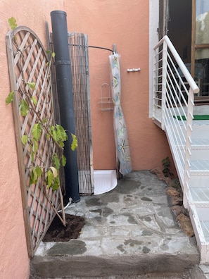 Eine Steintreppe führt zu einem Balkon mit einem Metallzaun und einem weißen Sonnenschirm.