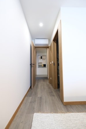 A hallway with wooden doors, a white carpet, and a ceiling light. - Casa Roca do Touro: Mountain View, Wi-Fi & Air Conditioning (Cabril)