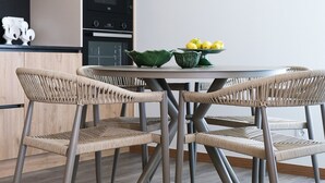 A modern kitchen with a dining area, featuring a wooden cabinet, a built-in oven, a microwave, and a table with chairs. - Casa Roca do Touro: Mountain View, Wi-Fi & Air Conditioning (Cabril)