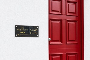 Une porte rouge avec une enseigne noire indiquant que des suites avec cuisine sont disponibles de 5 h à 6 h du matin et de 13 h à 16 h.