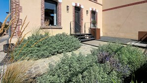 A building with a brick facade, a set of stairs leading to a door, and a small garden area with various plants. - La Maison du Port – Beach within walking distance, peaceful and comfortable (Dives-sur-Mer)