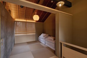 A room with tatami flooring, a low bed with pillows, a wooden ceiling, and a hanging light fixture. - NEW | Private Kyoto Machiya | Walking Distance to Gion & Shirakawa (京都市京都市東山区北木之元町)