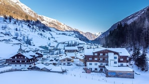 Een besneeuwd dorp met traditionele houten gebouwen, waaronder het hotel 'HEIMAT HOTEL'.