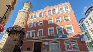 A red building with a tower, multiple windows, and a door.