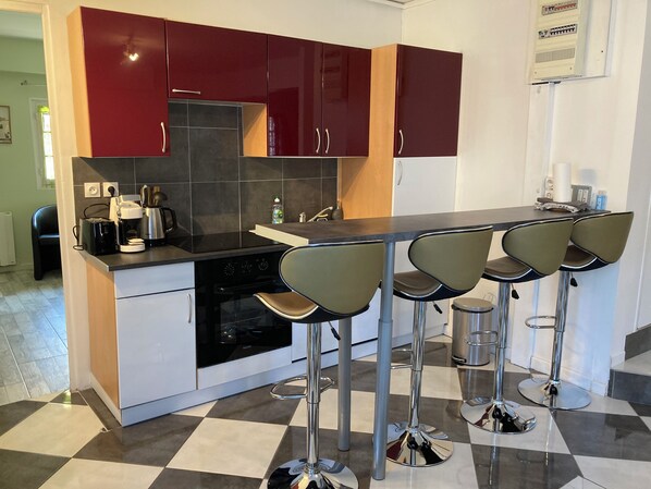A modern kitchen with a central island, bar stools, and a built-in oven.