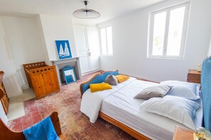 A bedroom with a bed, a wooden chest, a mirror, a fireplace, and a window. - La Parenthèse d’Honfleur Cosy | 2 Bedrooms & Private Courtyard (La Rivière-Saint-Sauveur)