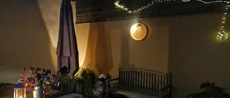 Eine Terrasse im Freien mit Tisch, Stühlen, einer Bank und Lichterketten.