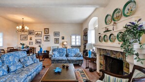 Ein Wohnzimmer mit gestreiften Sofas, einem Couchtisch, einem Kamin und dekorativen Wandtellern.