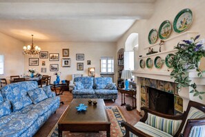 Ein Wohnzimmer mit gestreiften Sofas, einem Couchtisch, einem Kamin und dekorativen Wandtellern.