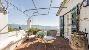 Eine Terrasse mit Tisch und Stühlen, einem Blumentopf und Blick auf Berge.