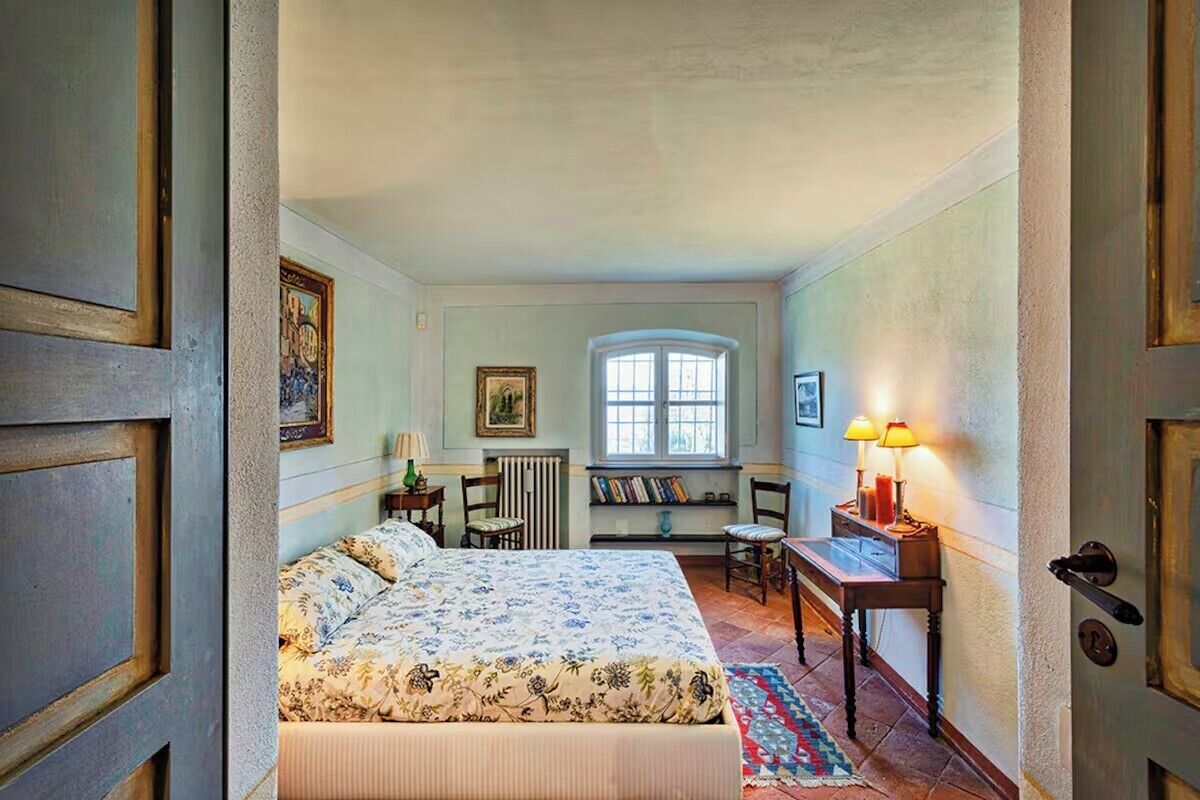 Ein Schlafzimmer mit Bett, Schreibtisch, Stuhl, Heizkörper und Fenster.