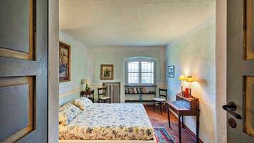 Een slaapkamer met een bed, een bureau, een stoel, een radiator en een raam.
