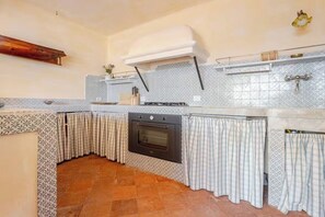 Une cuisine dotée d’un four encastré, d’un luminaire suspendu et de carreaux décoratifs sur le plan de travail.