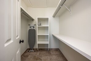A laundry room with a wall-mounted ironing board, shelves, and a door. - The Chile Pad is a charming remodeled 3 bedroom, 2 bathroom townhouse. (Las Cruces)